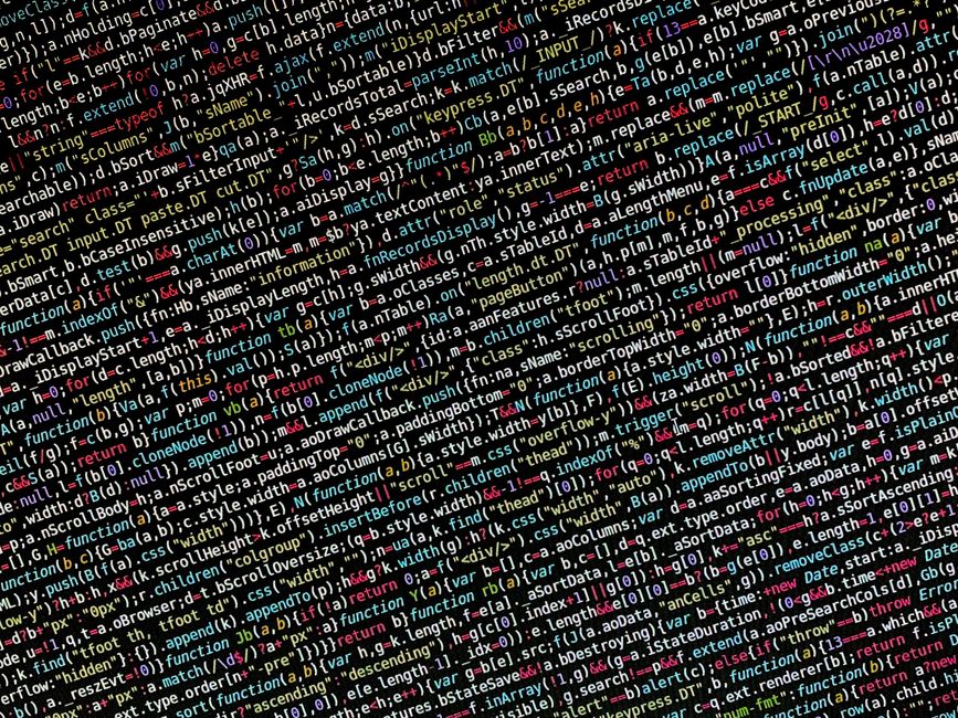 A close-up photograph of a printed computer code with multicoloured syntax highlighting, including various keywords, functions, and variables in red, green, yellow, and white text on a black backgroun